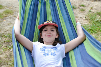 A beautiful girl lies in a yellow hammock on a background of blurred greenery.