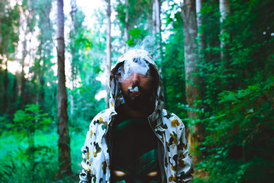 Man smoking against trees in forest