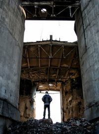 Rear view of man standing under bridge