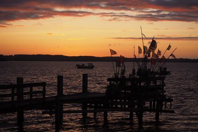 Silhouette pier over sea against sky during sunset