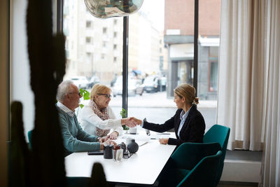 Female estate agent congratulating senior couple for new house at office