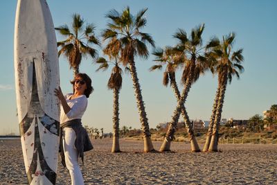 Rear view of woman standing on beach against sky