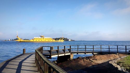 Yellow cargo ship in sea against sky