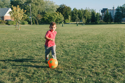 Boy playing with ball on grassy land in park