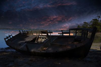 Abandoned boat moored on shore against sky