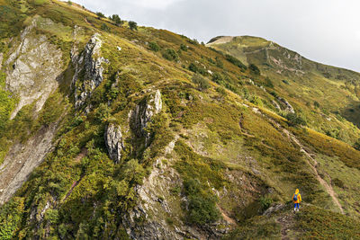 Young woman in yellow hoodie with backpack hiking in picturesque mountain healthy active lifestyle