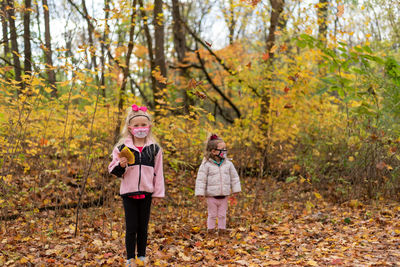 Full length of a woman standing with autumn leaves