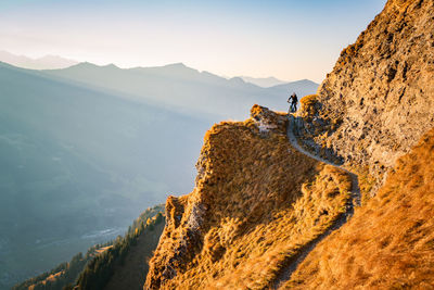 Man cycling on mountain road against sky