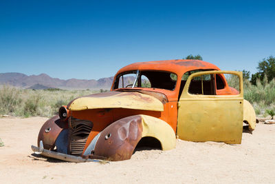 Abandoned car at desert on sunny day