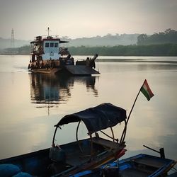 Fishing boat moored on lake against sky