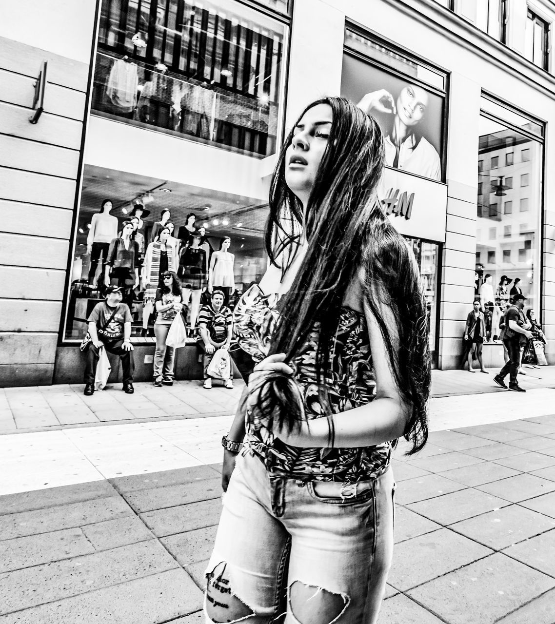 city, architecture, street, lifestyles, one person, building exterior, real people, built structure, incidental people, long hair, young adult, casual clothing, leisure activity, standing, city life, women, hairstyle, day, front view, hair, beautiful woman, outdoors, teenager
