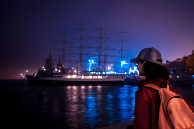 Man on illuminated ship at sea against sky at night