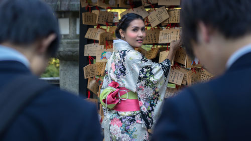 Rear view of man holding woman standing against blurred background