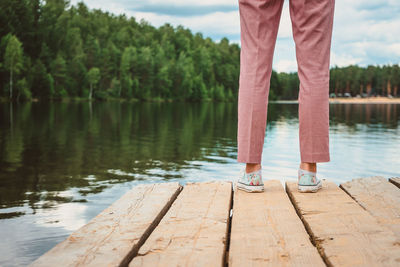 Low section of woman standing by lake