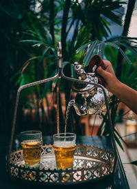 Cropped hand of person pouring drinks in glass outdoors