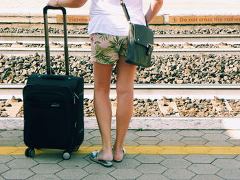 Low section of woman standing at railroad station