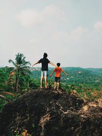 Rear view of man with arms outstretched standing on field