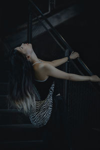 Rear view of young woman standing against black background