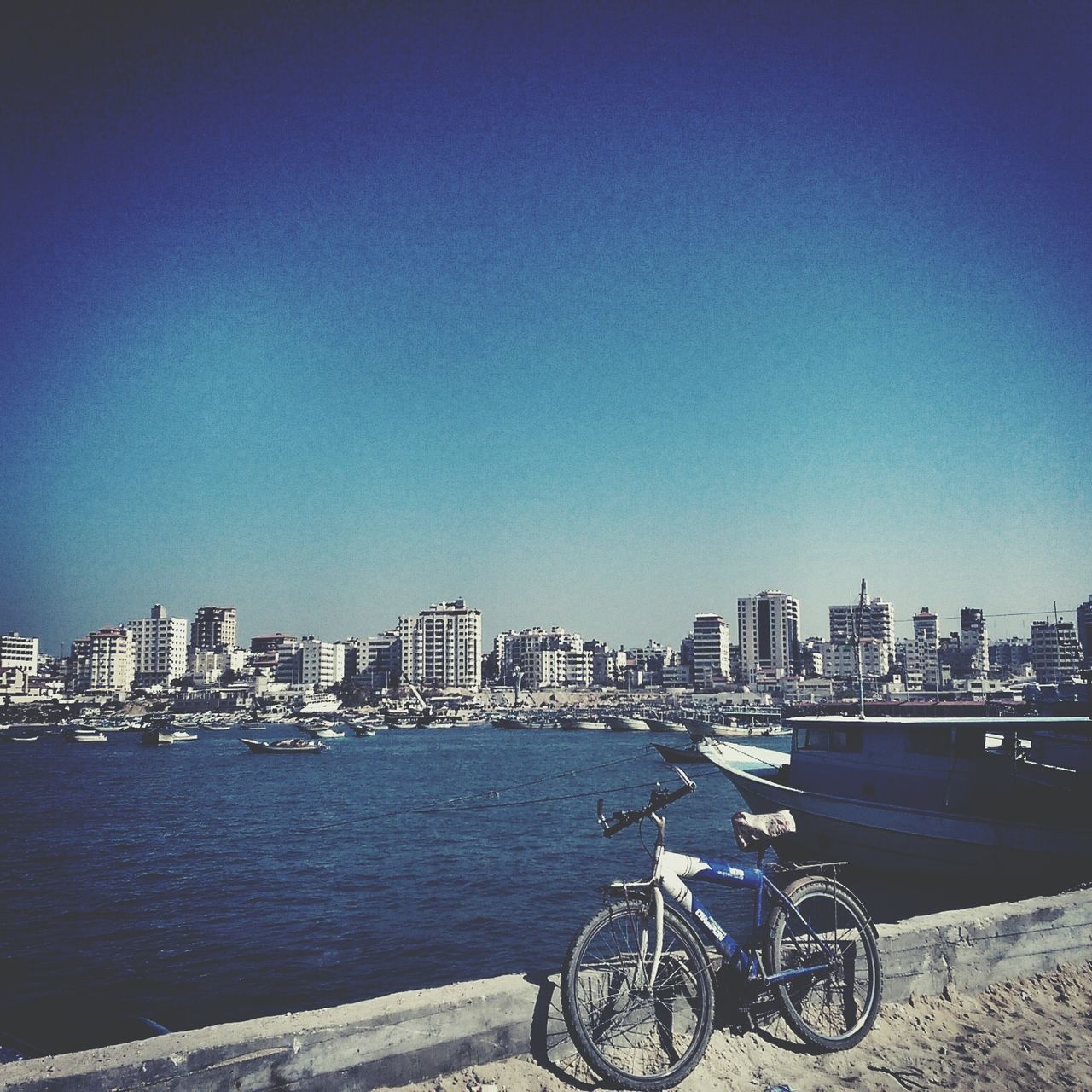 building exterior, transportation, architecture, mode of transport, built structure, water, nautical vessel, clear sky, city, copy space, blue, boat, river, bicycle, cityscape, waterfront, moored, land vehicle, sea, parking