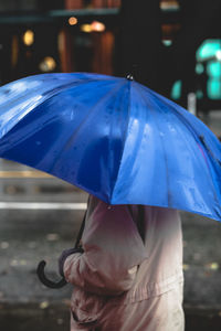 Midsection of man holding umbrella in rain