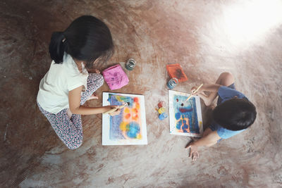 High angle view of siblings lying on floor