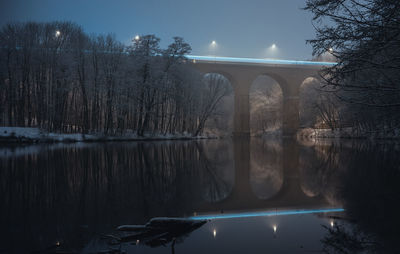 Bridge over river against sky at night