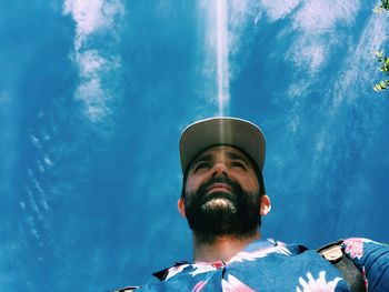 Low angle view of man against blue sky during sunny day