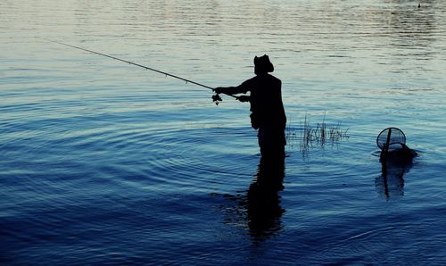 Silhouette man fishing in lake