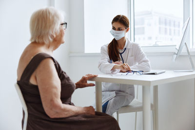 Doctor wearing mask taking to patient