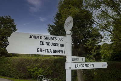 Information sign by road against sky