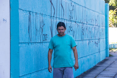 Portrait of young man standing against blue wall