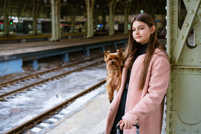 Young girl in pink coat at train station. beautiful woman stands on platform