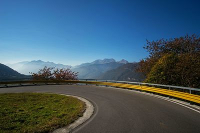 Road by mountain against clear blue sky