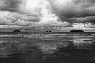 Scenic view of beach against cloudy sky