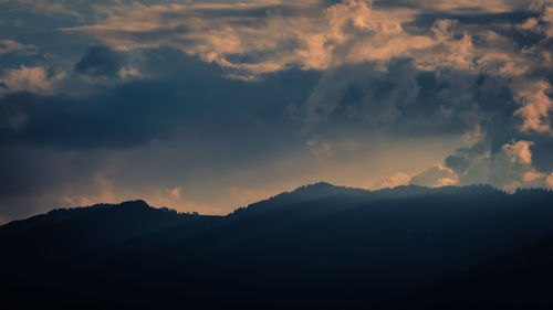 Scenic view of silhouette mountains against dramatic sky