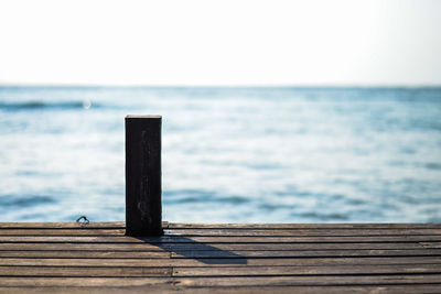Close-up of wooden pier over sea against clear sky