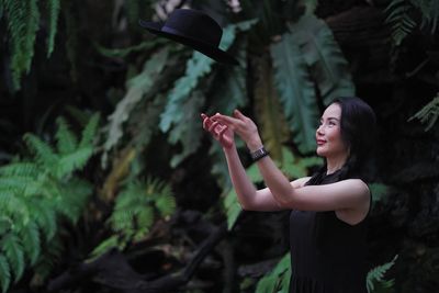 Side view of a smiling young woman holding plant