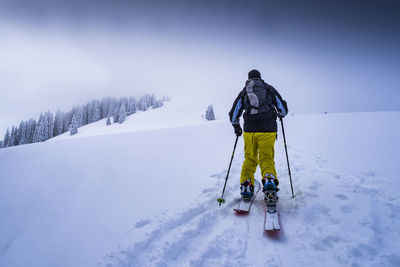 Rear view of man skiing on snow covered landscape