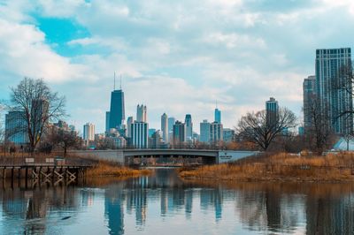 River by modern buildings against sky in city