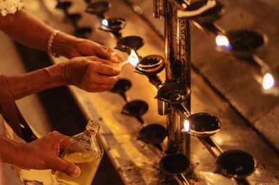 Cropped hands of people igniting diyas