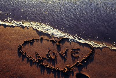High angle view of love with heart shape written on sandy beach