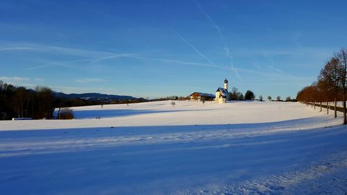 Snow covered landscape against blue sky