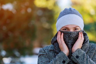 Portrait of young woman covering face with snow