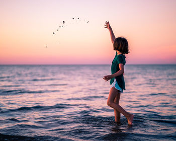 Full length of child on beach against sky during sunset