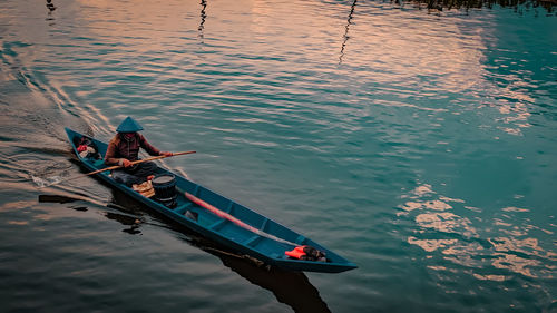 High angle view of man sitting on rowboat in lake