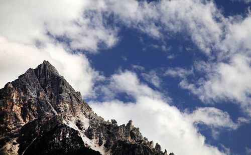 Low angle view of dolomites against cloudy sky