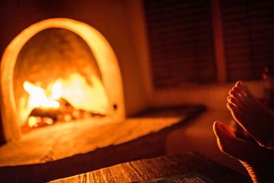 Low section of bare feet with fireplace in distance