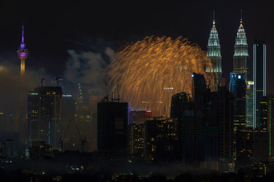 Firework display over illuminated buildings in city at night