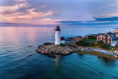 Lighthouse amidst sea and buildings against sky