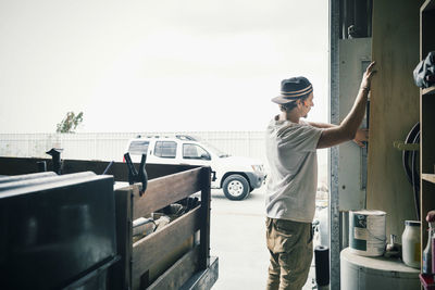 Side view of carpenter working outside workshop against sky